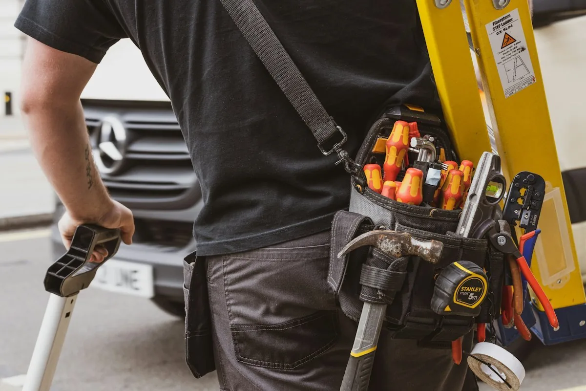 Technician carrying tools beside a work vehicle