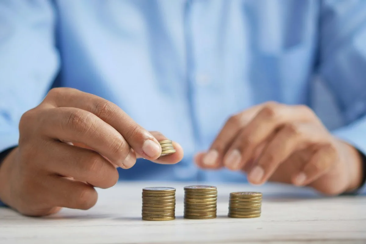 Person adding coins to savings stacks