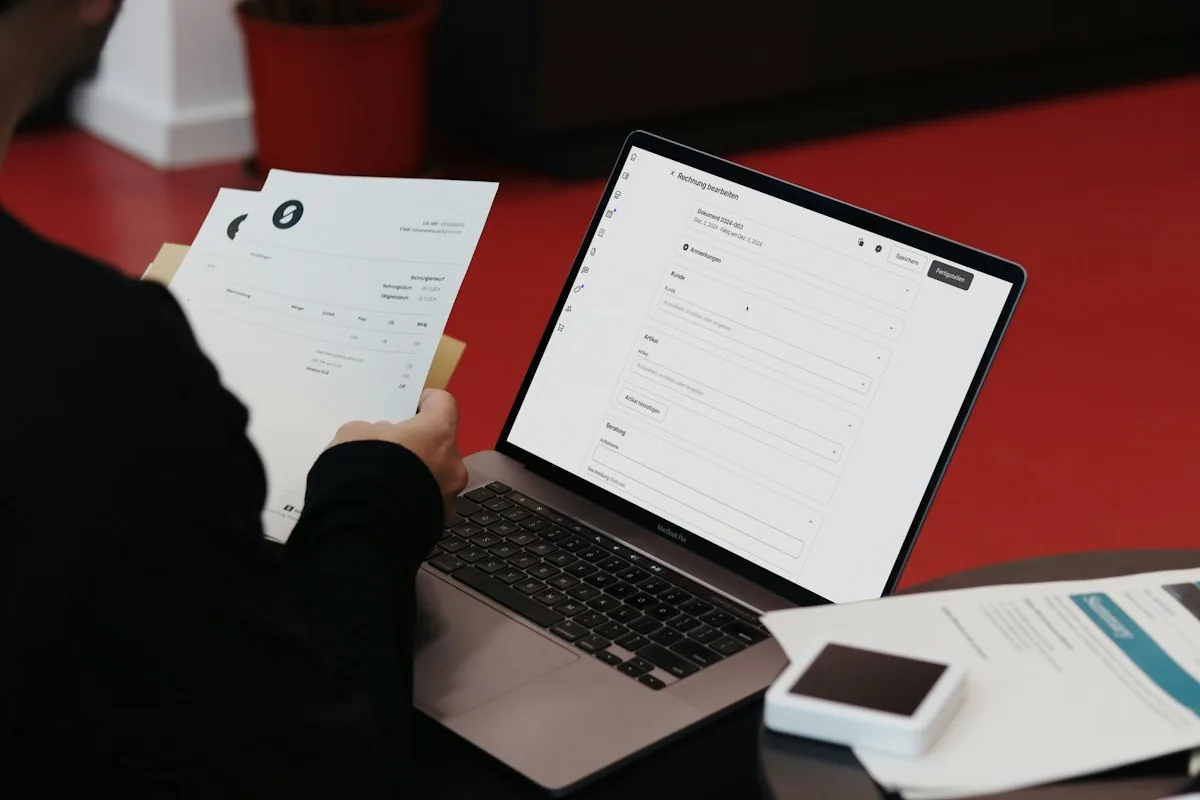 Business owner reviewing an invoice beside a laptop